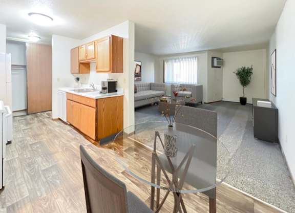 A modern kitchen with wooden cabinets and a glass table.