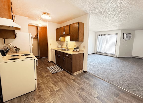 A kitchen with a white stove top oven and wooden flooring.