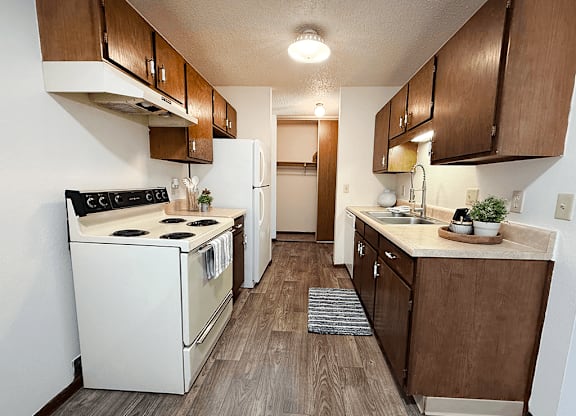 A kitchen with a white stove and brown cabinets.
