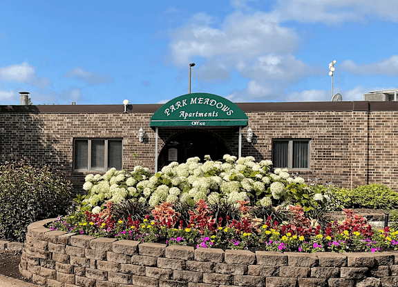 a flower bed in front of a brick building with a green awning