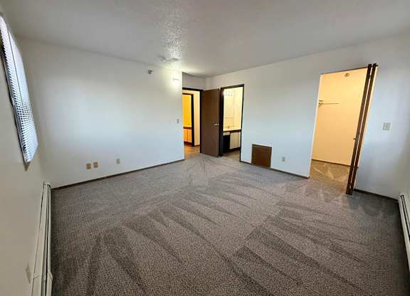 A room with carpeted floor and two doors.