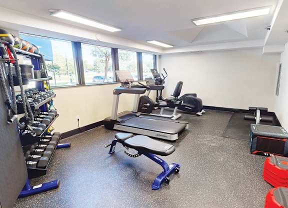 A gym room with a treadmill, weights, and other exercise equipment.