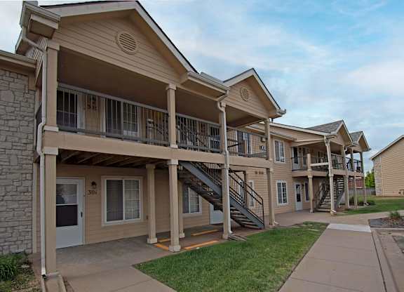 Apartment complex with stone pillars and a balcony.