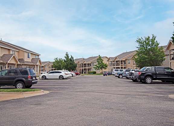 A parking lot with cars and apartment buildings in the background.