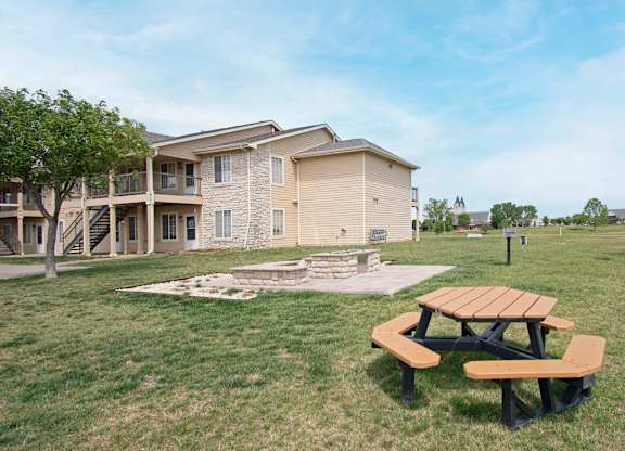 A picnic table sits in the grass in front of a building.