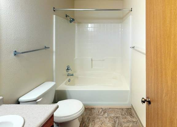 A white toilet sits next to a white bathtub in a small bathroom.
