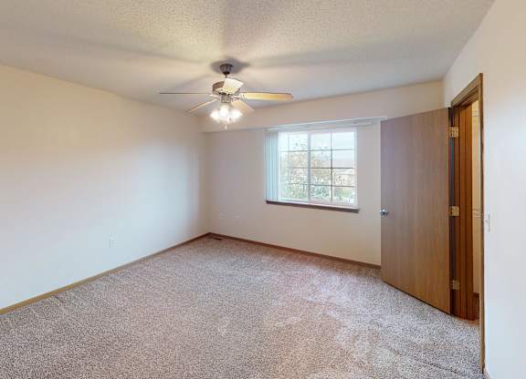 A room with a ceiling fan and carpeted floor.