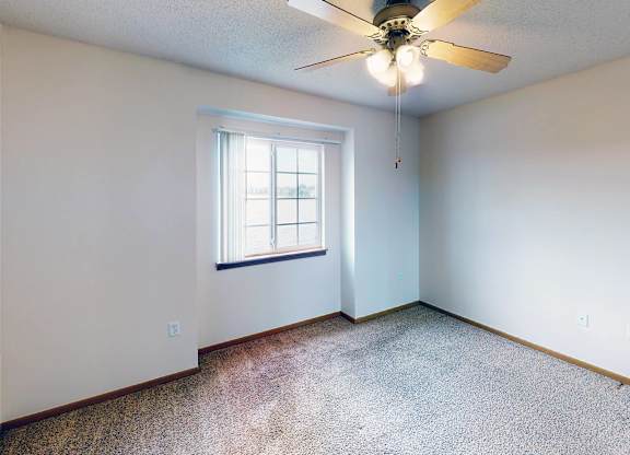 A room with a ceiling fan and a window.
