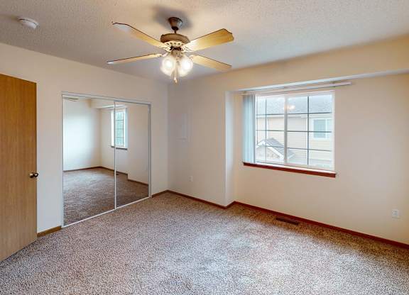 A room with a ceiling fan and a window.