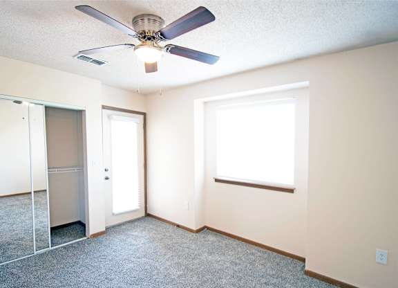 A room with a ceiling fan and a window.