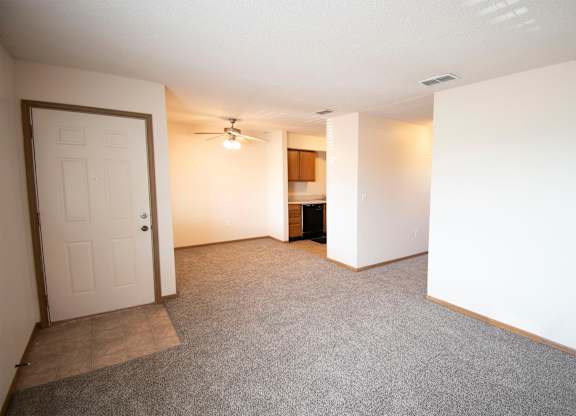 A room with a carpeted floor and a ceiling fan.