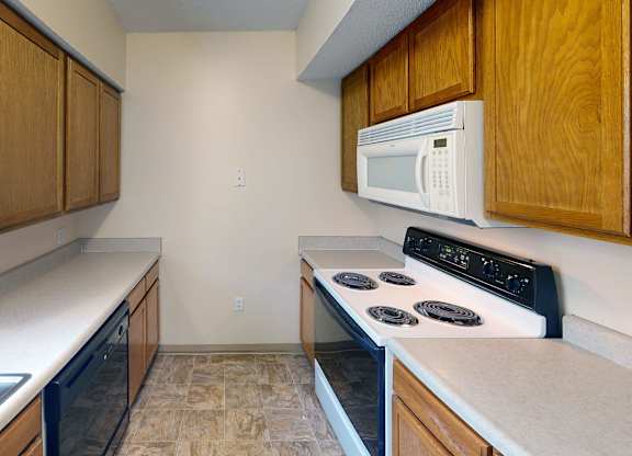 A kitchen with a white microwave above a stove and a sink to the left.
