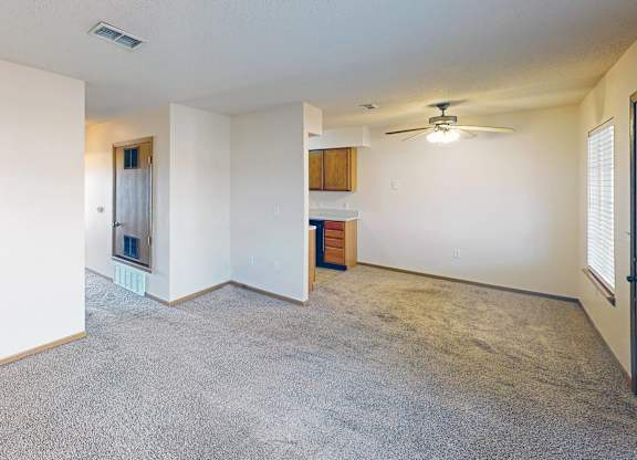 A spacious living room with a carpeted floor and a ceiling fan.