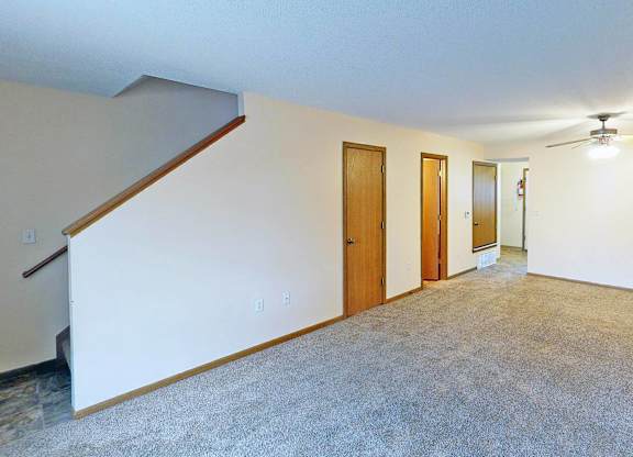 A room with a carpeted floor and a ceiling fan.