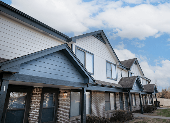 A row of houses with a blue sky and clouds in the background.