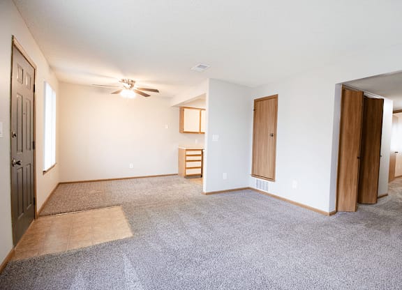 A room with a ceiling fan and a rug on the floor.