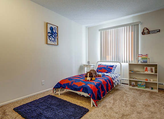 A bedroom with a bed, a shelf, and a picture on the wall.
