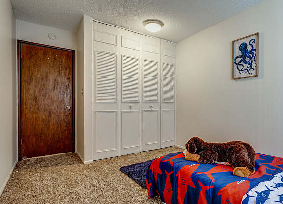 A dog sleeping on a bed in a room with a wooden door and white walls.