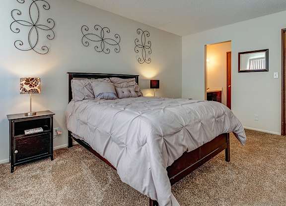 A bedroom with a large bed and a nightstand with a lamp.