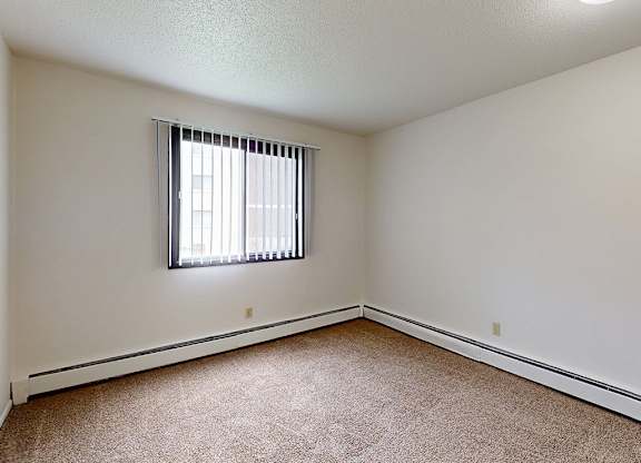 A room with a window and carpeted floor.