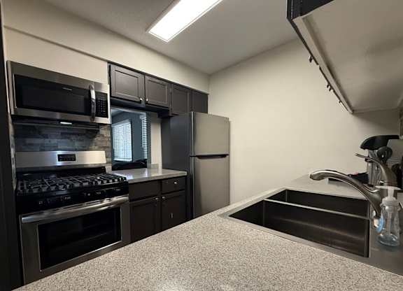 A kitchen with a stove, microwave, and refrigerator.