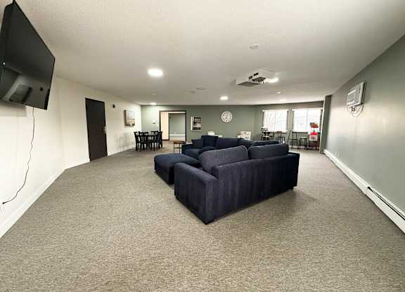 A living room with a grey sofa and a television on the wall.