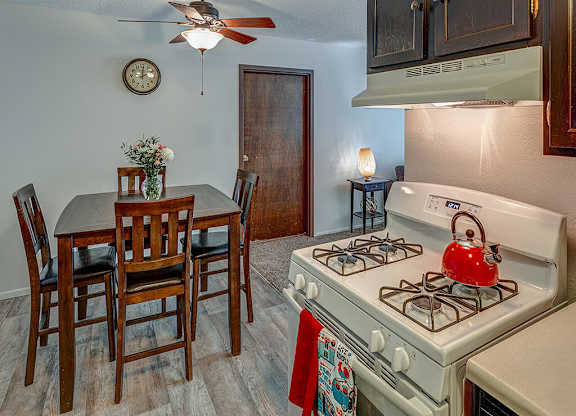 A kitchen with a white gas stove and a dining table with chairs.