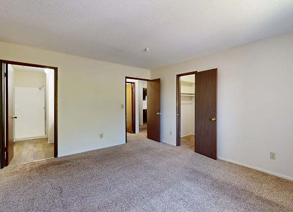A room with carpeted floor and white walls with four doors.
