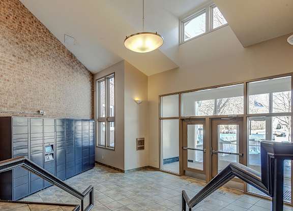 A hallway with a brick wall and a glass door.