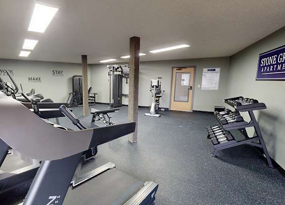 A gym room with a treadmill, weights, and a bench.