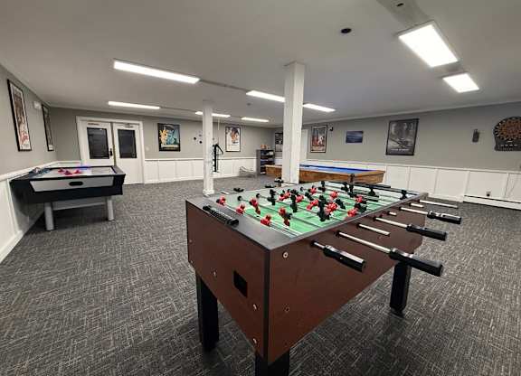 A foosball table is in the middle of a room with a pool table and a foosball table.