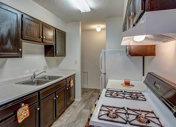 A kitchen with a white fridge, white stove, and brown cabinets.