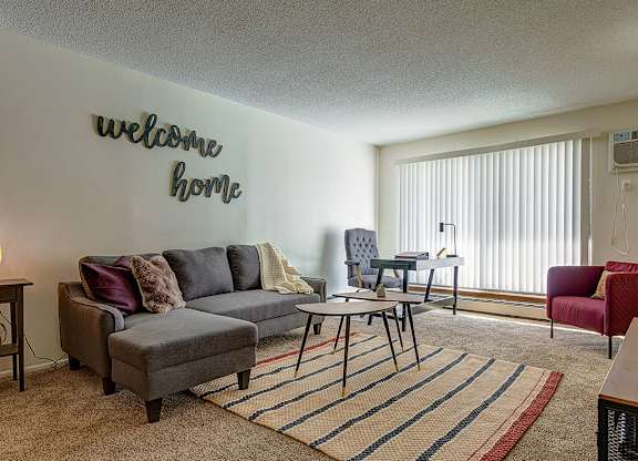 A living room with a grey sofa and a welcome home sign.