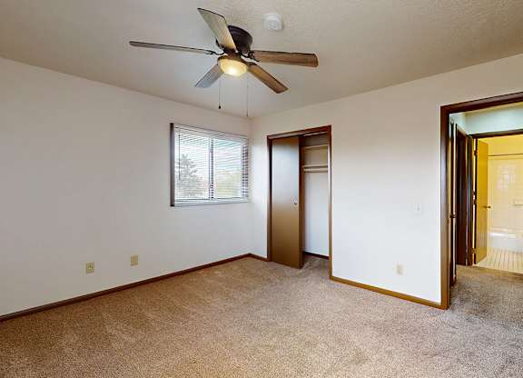 A room with a ceiling fan and a window.