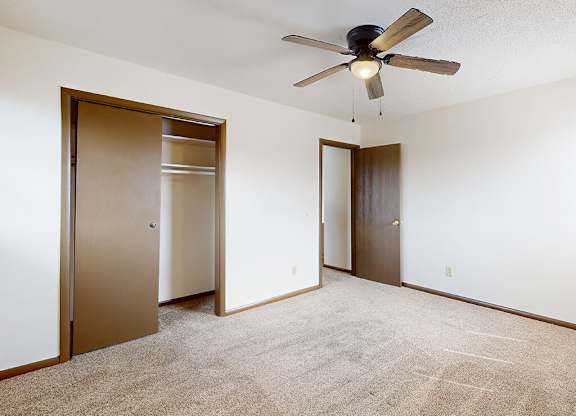 A room with a ceiling fan and two doors.