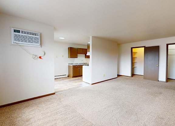 A spacious living room with a carpeted floor and a fireplace.