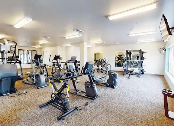 A spacious gym with a variety of cardio exercise equipment The Plaza Apartments.
