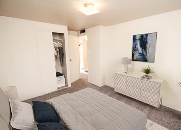 a bedroom with a bed and a dresser with a lamp