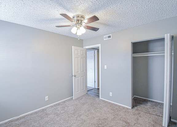 an empty room with a ceiling fan and a door to a closet