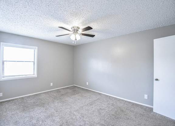 an empty room with a ceiling fan and a window