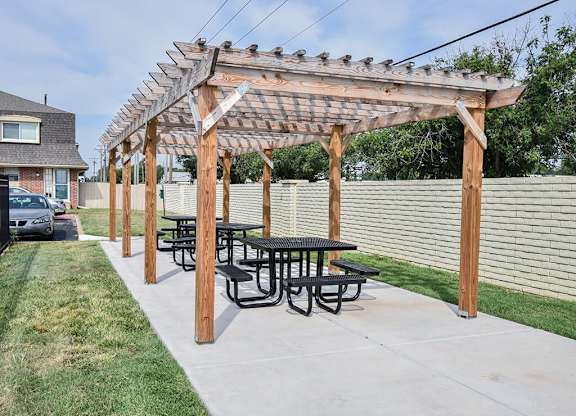 a picnic table under a wooden pergola in a backyard