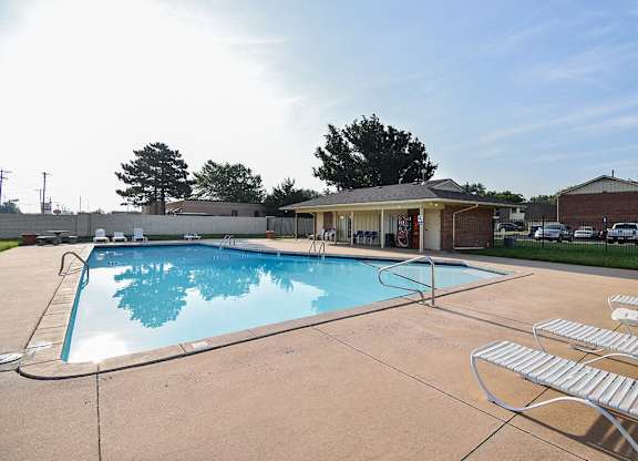 a swimming pool with chairs around it in front of a clubhouse