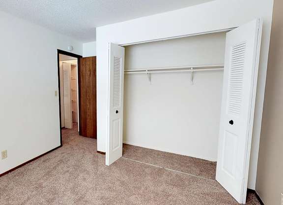A white closet with a door and a shelf.
