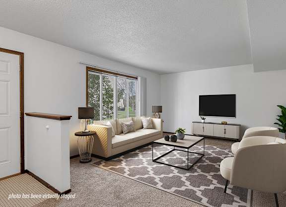 A living room with a white sofa, a black coffee table, and a flat screen TV.