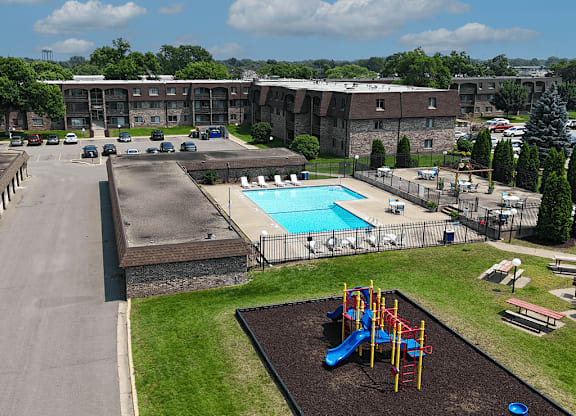 A playground with a slide and a pool in the background.