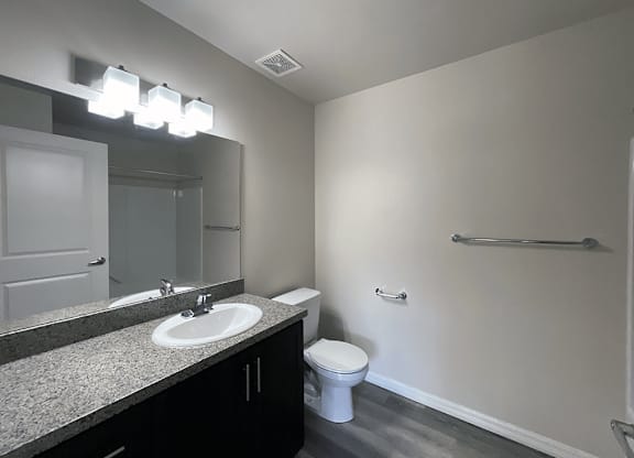 Apartment bathroom with a toilet, sink, and big mirror