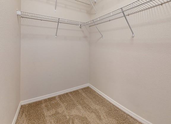 Empty room with a carpeted floor and a metal rack on the wall.