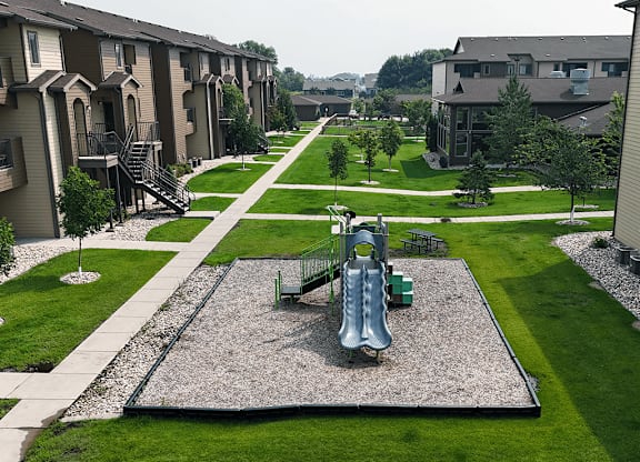 A playground with a slide in the middle of a grassy area.