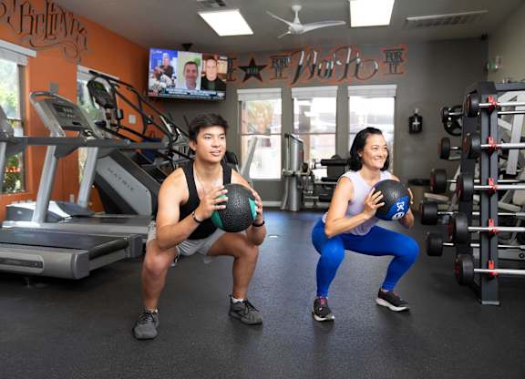 A man and a woman are exercising in a gym.