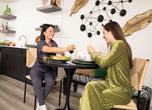 Two women are sitting at a table in a modern kitchen.